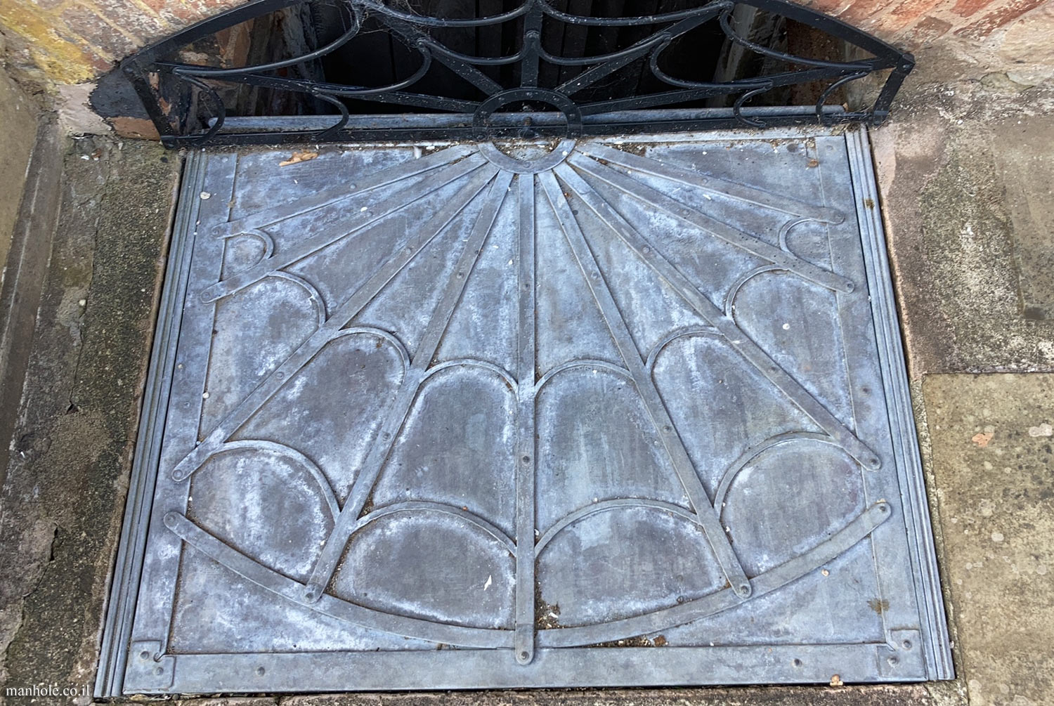Ludlow - A lid with a background resembling a cobweb and a drain opening at the end