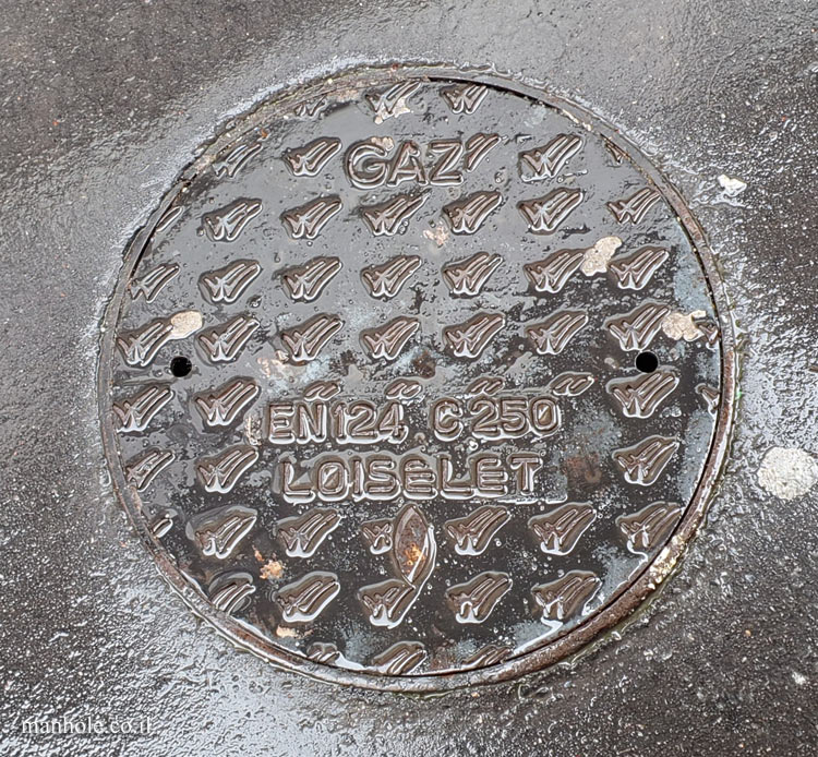 Paris - Gas manhole cover with a background with V marks