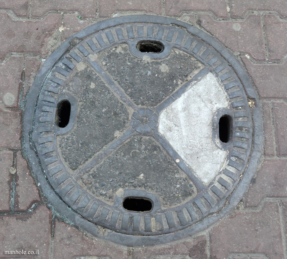 Warsaw - Concrete cover with a metal frame, crossed by metal strips and a flower in the center